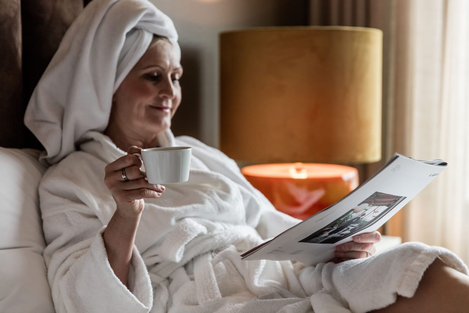 Woman reading newspaper in hotel room