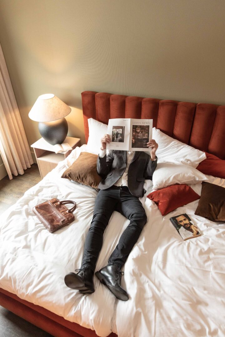 man ligger i säng och läser tidning