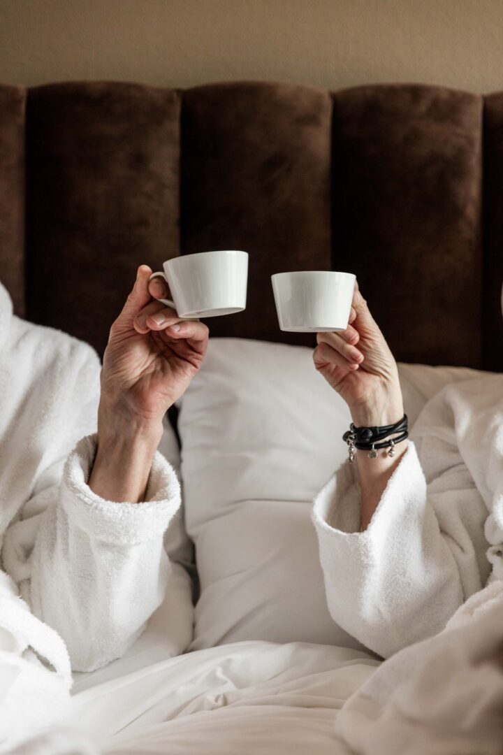 Par dricker kaffe i säng på hotellrum